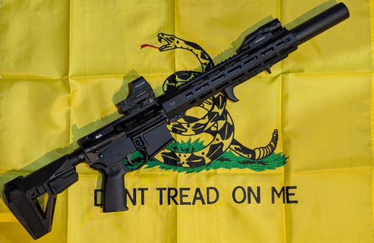 Black rifle on a yellow flag with a snake design and 'Don't Tread on Me' text.
